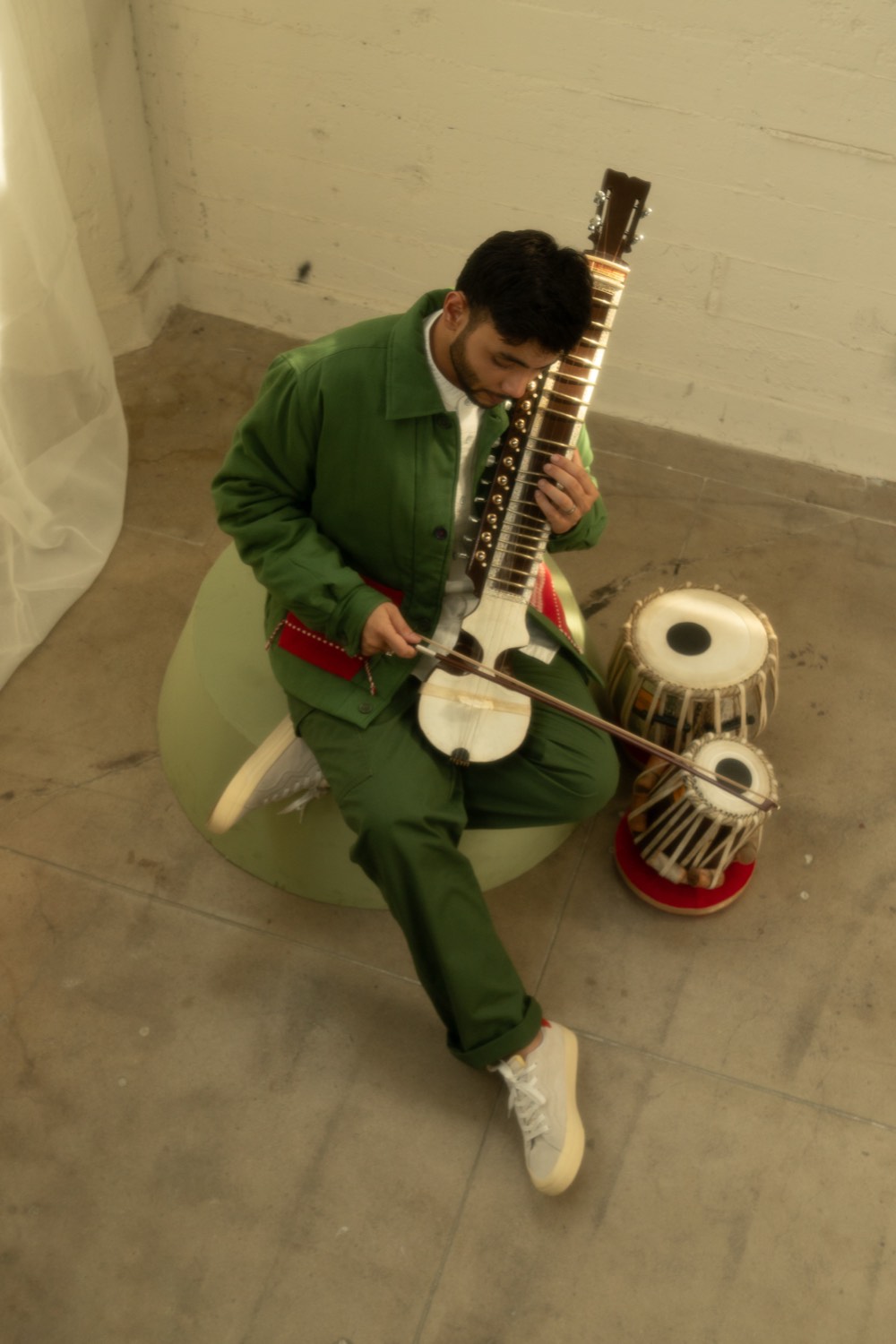 Zeek playing sitar beside a pair of tabla